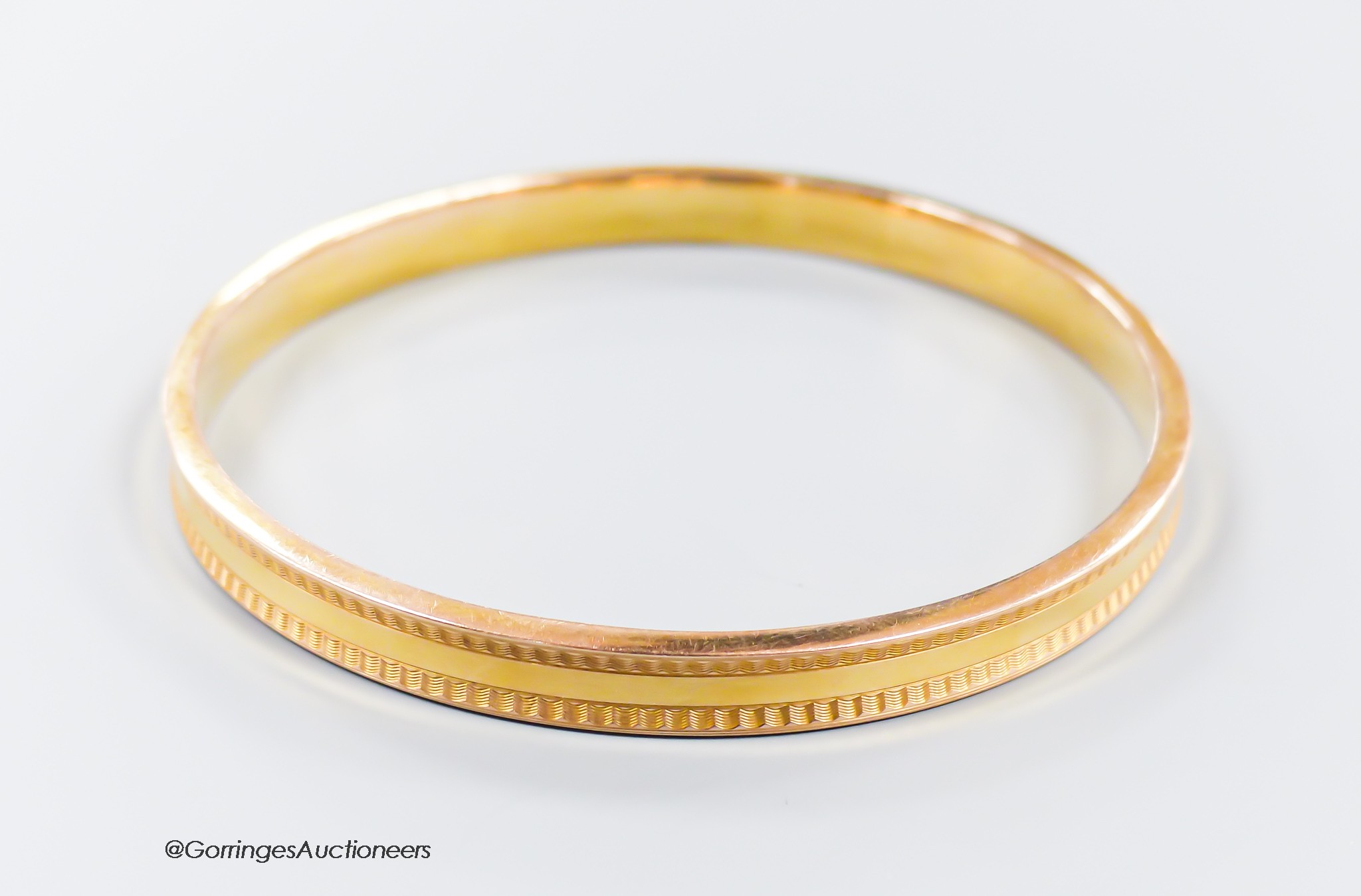 A 1930's engine turned 9ct gold bangle, interior diameter 73mm, 9 grams.